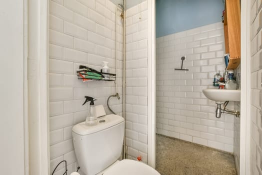 a white toilet in a small bathroom with blue walls and floor tiles on the wall behind it is an open door
