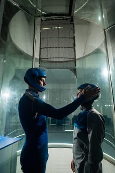 A male instructor teaches a woman how to fly in a wind tunnel. Free fall simulator