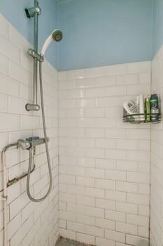 a bathroom with white tiles on the walls, and a shower head mounted to the wall next to the tub