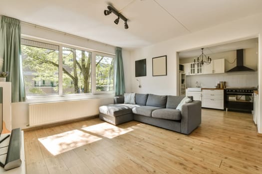a living room with wood flooring and large windows looking out onto the trees in the area is very sunny