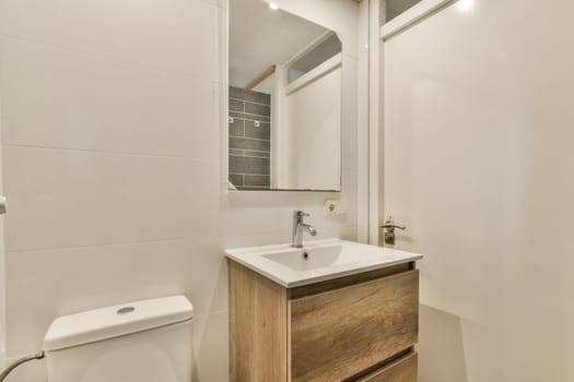 a small bathroom with a sink and toilet in the corner, along with a mirror on the wall above it