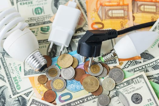 The concept of the energy crisis, price increases. Euro and dollar banknotes, coins on the background of a lamp, plug, cord. Tax time, bill payment, calculator for counting