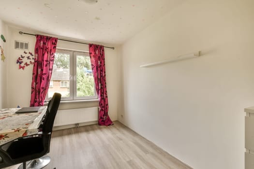 a dining room with white walls and pink curtains on the windowsills, there is a black chair next to the table