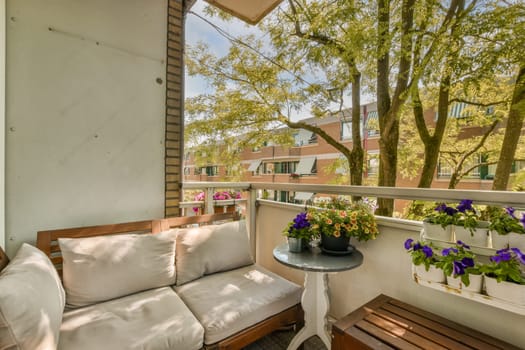 a balcony with flowers and plants on the outside furniture, as seen from an open window in this apartment's front yard
