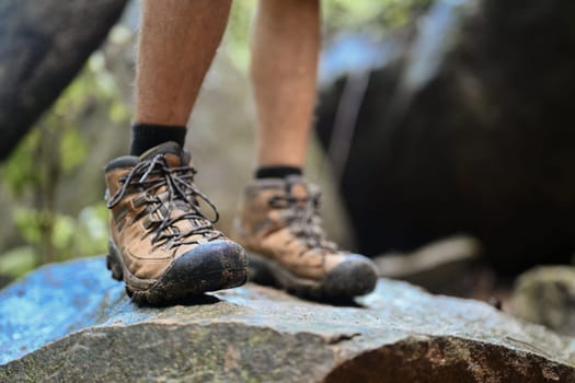 Unrecognizable traveler in trekking shoes standing on a rock. Traveling and adventure concept.