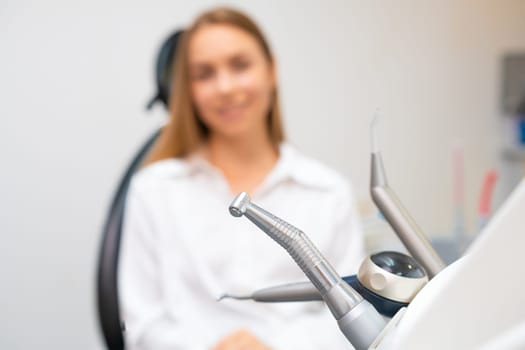 Closeup of dental drills in dentists office with patient on the background.