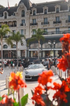 Monaco, Monte-Carlo, 22 October 2022: Square Casino Monte-Carlo at sunset, luxury cars, famous Hotel de Paris, wealth life, tourists take pictures of the landmark, pine trees, flowers. High quality photo