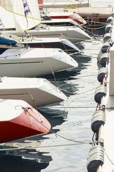 Monaco, Monte-Carlo, 29 September 2022: a lot of sail boats are moored in the new Yacht Club at sunny day, no wind, teams is waiting race, port Hercules, bow with sails. High quality photo