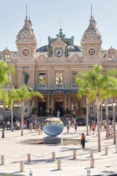 Monaco, Monte-Carlo, 21 October 2022: Square Casino Monte-Carlo at sunny day, wealth life, tourists take pictures of the landmark, pine trees, blue sky. High quality photo