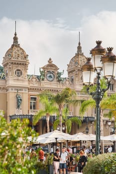 Monaco, Monte-Carlo, 21 October 2022: Square Casino Monte-Carlo at sunny day, wealth life, tourists take pictures of the landmark, pine trees, blue sky. High quality photo