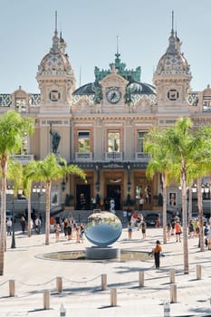 Monaco, Monte-Carlo, 21 October 2022: Square Casino Monte-Carlo at sunny day, wealth life, tourists take pictures of the landmark, pine trees, blue sky. High quality photo