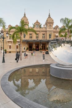 Monaco, Monte-Carlo, 21 October 2022: Square Casino Monte-Carlo at cloudy day, a lot of luxury cars, Hotel de Paris, wealth life, tourists take pictures of the landmark, pine trees, blue sky, flowers. High quality photo