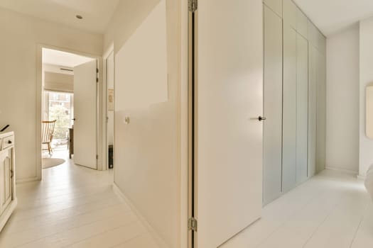 a bathroom with white walls and wood flooring on the wall, there is an open door leading to another room