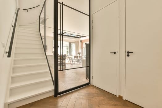 the inside of a house with wood flooring and white walls, stairs leading up to an open door that leads to another room