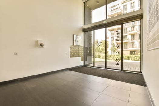 an empty room with glass doors and black tiles on the floor, in front of a large white brick wall