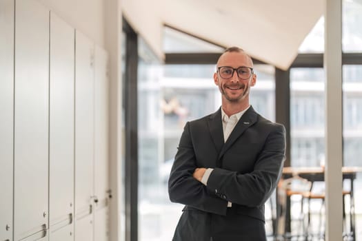 Portrait of an attractive young businessman A successful business executive stands with his arms crossed in his office with a happy smile on his face..