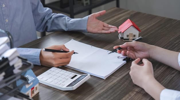 House model with agent and customer discussing for contract to buy, get insurance or loan real estate or property.