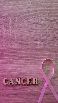 Wooden Pink Background image Breast cancer Awareness is celebrated in October Month. The inscription with the symbol is a pink ribbon. Close-up, vertical, copy space, paste text