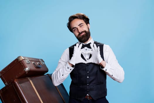 Hotel porter doing heart shape sign in studio and displaying romantic emotions, professional tourism occupation. Young man being sweet and presenting love romance symbol on camera.