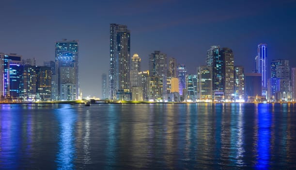 Night landscape of the embankment of the emirate of Sharjah, United Arab Emirates.