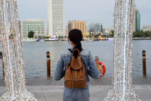 A young woman with a backpack on her back admires the architecture in the old Dubai Creek of Deira. Back view. Journey through the Persian Gulf