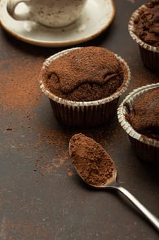 Chocolate and cocoa browny muffins with coffee cappuccino in cup angle view on brown rustic stone background, sweet homemade dark chocolate cupcakes.