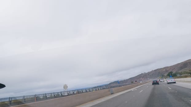 Los Angeles, California, USA-December 4, 2022-POV-Driving along Highway 101 near Rincon Beach, California, amidst a gloomy, cloudy winter day.