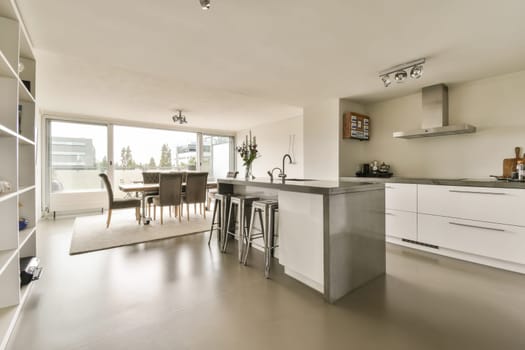 a kitchen and dining area in a modern home with white cabinets, stainless appliances and an island bench on the floor