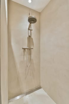 a shower in the corner of a room with beige walls and white tiles on the floor, there is a light coming from above