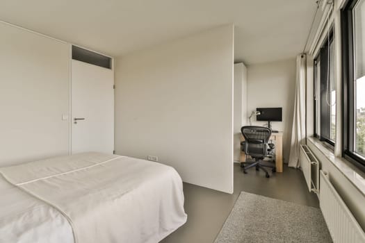 a bedroom with a bed, desk and television set in the corner next to the window that looks out onto the street