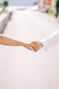 Man holds woman hand while standing on the road. Cropped. Faceless. High quality photo