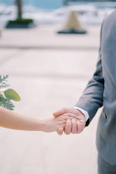 Groom holds bride hand with a bouquet. Cropped. Faceless. High quality photo