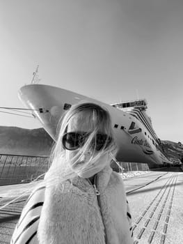 Little girl in sunglasses with flying hair on the background of a cruise liner. Black and white photo. High quality photo