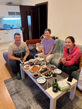 Two women and a man are sitting at a set table on a sofa. High quality photo