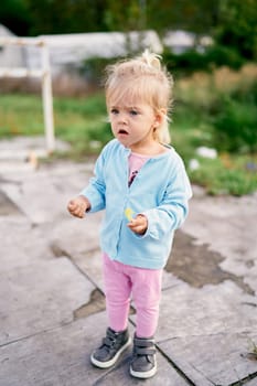 Little girl stands in the yard with her mouth open in surprise. High quality photo