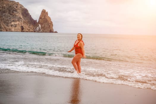 Woman in a bathing suit at the sea. A fat young woman in a red swimsuit enters the water during the surf.