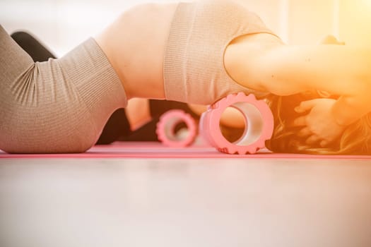 Athletic women doing fascia exercises on the floor with a foam roller massage tool to relieve back tension and relieve muscle pain. The concept of physiotherapy and stretching training.