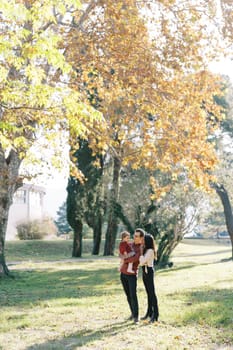 Mom put her hands on dad shoulder with a little girl in his arms in the park. High quality photo