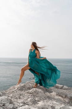 Woman sea trevel green dress. Side view a happy woman with long hair in a long mint dress posing on a beach with calm sea bokeh lights on sunny day. Girl on the nature on blue sky background