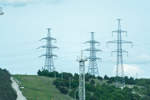 High voltage towers with sky background. Power line support with wires for electricity transmission. High voltage grid tower with wire cable at distribution station. Energy industry, energy saving.