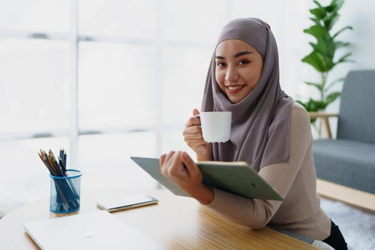 Muslim undergraduate student drinks coffee while read studying at home