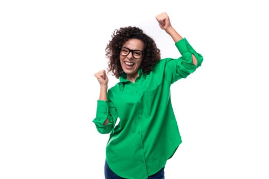 Charming slender young employee of the company woman with black hair is dressed in a green shirt is experiencing happiness.