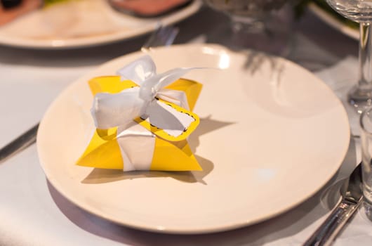 Close-up of bonbonniere on the table. Yellow Bonbonniere on the plate