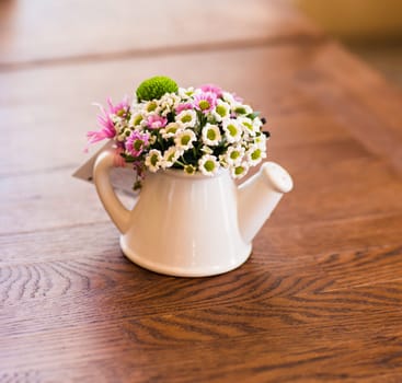 Artificial flowers in small decorative white watering