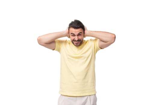 portrait of a fashionable young smart european guy with stubble and mustache dressed in a light yellow t-shirt on a white background.