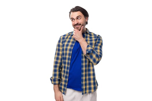 smart brunette macho man with a beard and mustache in a blue shirt on a white background with copy space.