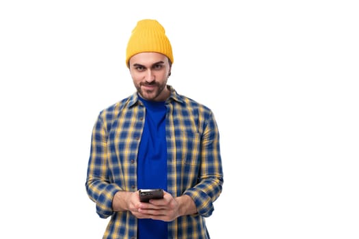 young brutal brunette man with a beard and mustache chatting on a mobile phone in social networks.