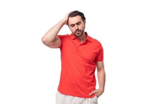 young caucasian brunette man with beard dressed in casual red t-shirt on studio background with copy space.