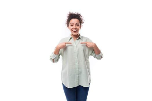 pretty young black-haired curly woman with careless styling bun in a shirt on a white background.