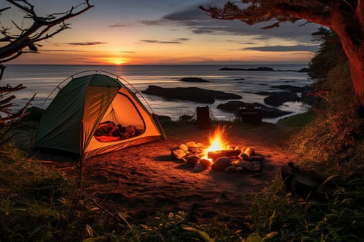 Camping by the sea. Tent and fire at sunset.